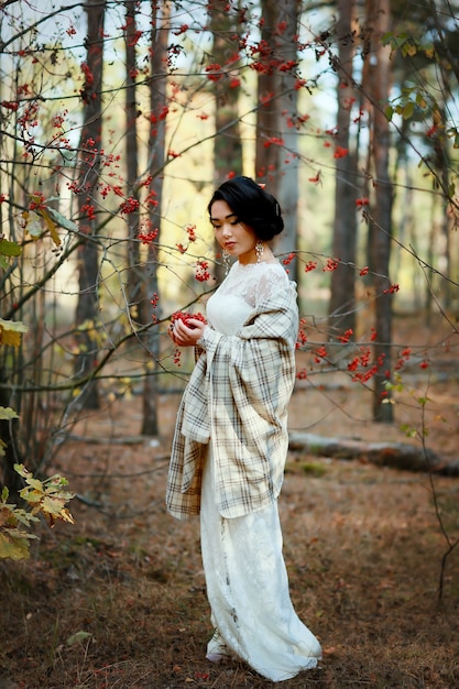 Hermosa mujer asiática en un vestido de novia en el bosque