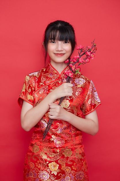 Hermosa mujer asiática en vestido rojo chino tradicional con rama de sakura