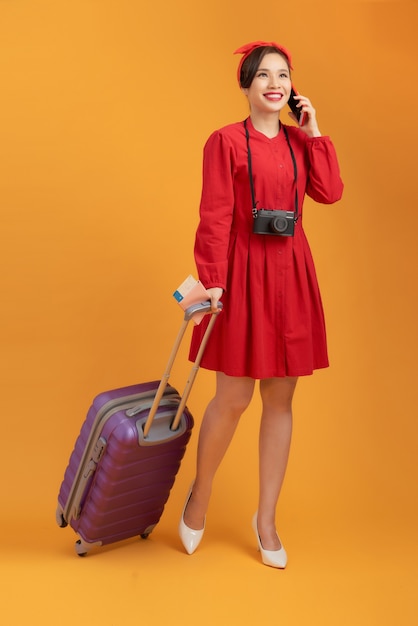 Hermosa mujer asiática con un vestido rojo y de pie sobre un fondo naranja