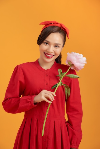 Hermosa mujer asiática con un vestido rojo y de pie sobre un fondo naranja