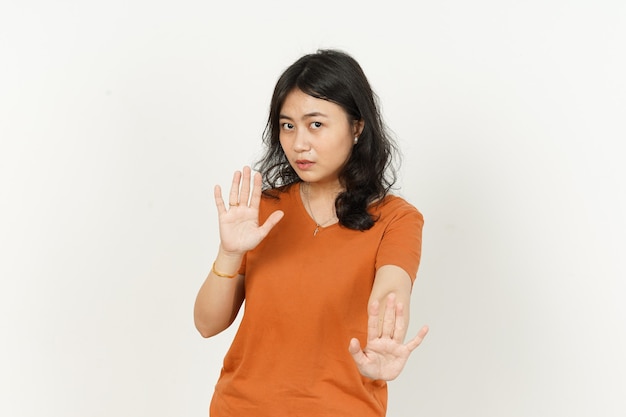 Hermosa mujer asiática vistiendo camiseta de color naranja detener el gesto de la mano aislado sobre fondo blanco.