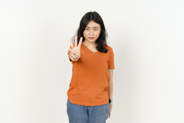 Hermosa mujer asiática vistiendo camiseta de color naranja mostrando tres dedos aislado sobre fondo blanco.