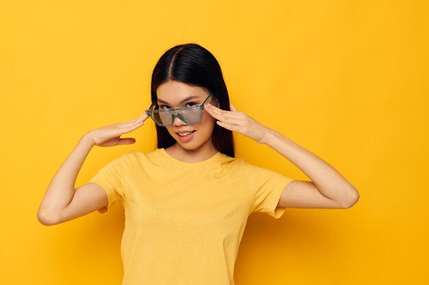 Hermosa mujer de aspecto asiático en moda de gafas de camiseta amarilla