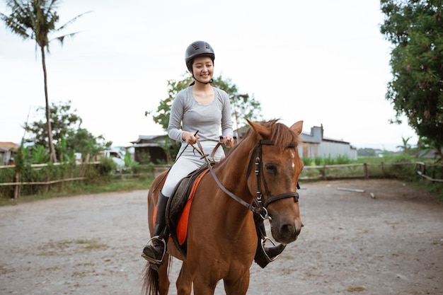 Hermosa mujer atleta ecuestre practicando equitación en el fondo al aire libre