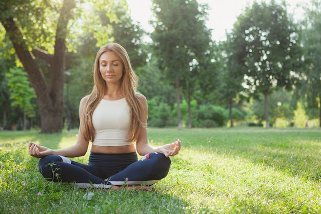 Hermosa mujer atlética haciendo yoga en el parque