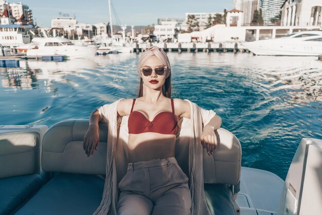 Hermosa mujer atractiva con gafas de sol descansa en su yate bajo las velas del sol en el mar Caribe