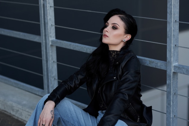 Foto hermosa mujer audaz en una chaqueta de cuero negro y jeans posando al aire libre