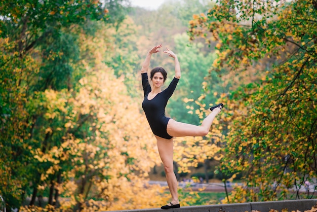 Hermosa mujer, bailarina, atleta en entrenamiento de traje negro en el parque