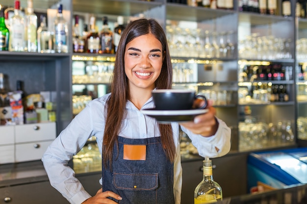 Hermosa mujer barista sostiene una taza con café caliente