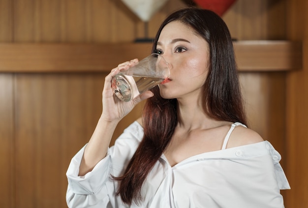 hermosa mujer bebiendo agua en la sala de cocina