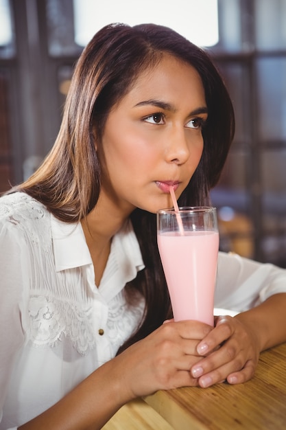 Una hermosa mujer bebiendo un batido rosa