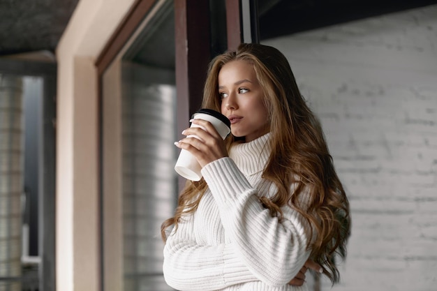 Hermosa mujer bebiendo café Chica sostiene taza de papel de café caliente