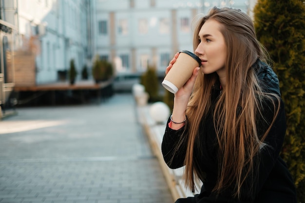 Hermosa mujer bebiendo café para llevar en el primer plano de la calle Estudiante femenina para un paseo Pausa para el café