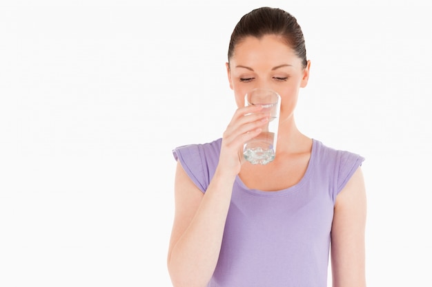 Hermosa mujer bebiendo un vaso de agua mientras está de pie