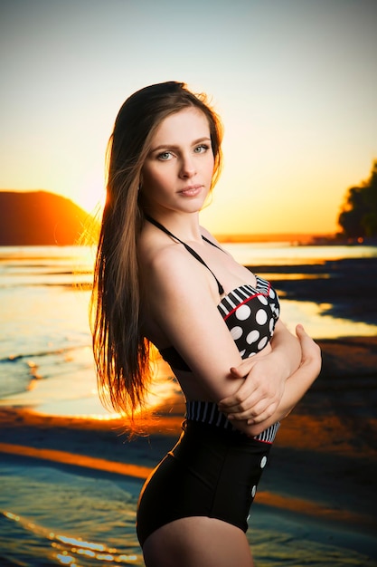 Hermosa mujer en bikini en el fondo del atardecer. Chica delgada posando en traje de baño