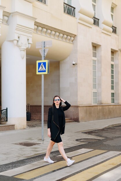 Hermosa mujer blanca con un vestido negro sobre un fondo de un paisaje urbano