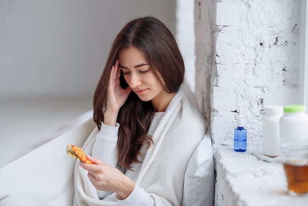 Hermosa mujer con blíster con pastillas en la mano