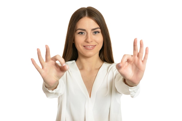 Hermosa mujer en blusa mostrando signo ok sobre fondo blanco.