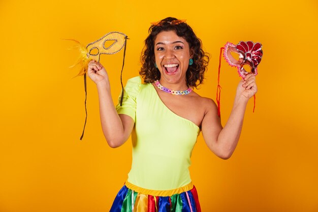 Foto hermosa mujer brasileña afroamericana en ropa de carnaval con dos máscaras de carnaval