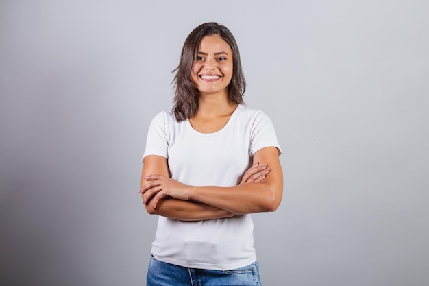 Hermosa mujer brasileña con los brazos cruzados denim y blanco optimista sonriendo