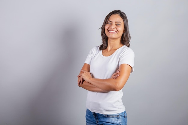 Hermosa mujer brasileña con los brazos cruzados denim y blanco optimista sonriendo