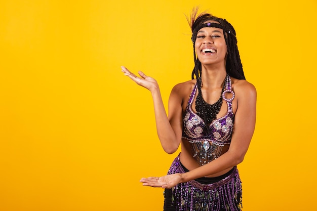 Hermosa mujer brasileña negra con ropa de carnaval morada presentando algo al lado del anuncio