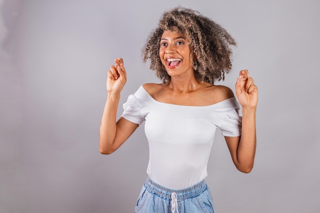 Hermosa mujer brasileña negra ropa casual dedos cruzados signo de la suerte animando deseando