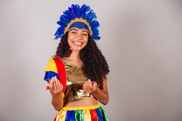 Hermosa mujer brasileña negra con ropa de frevo carnaval en tocado de plumas de carnaval invitando a las manos