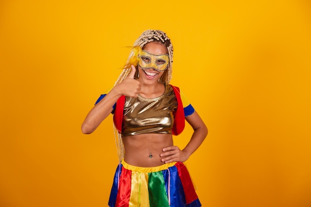 Hermosa mujer brasileña negra vestida con ropa de carnaval enmascara fondo amarillo como signo