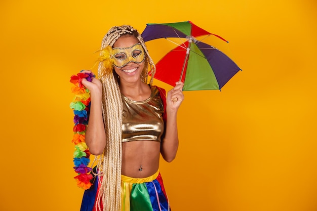 Hermosa mujer brasileña negra vestida con ropa de carnaval máscara de fondo amarillo con collar de flores