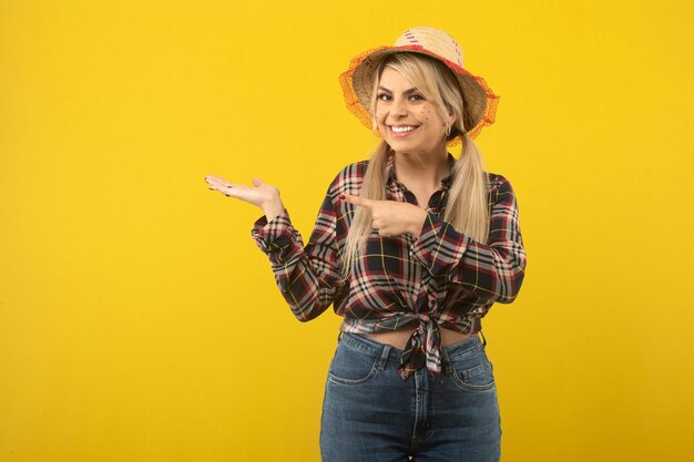 Hermosa mujer brasileña con ropa de festa junina sobre fondo amarillo