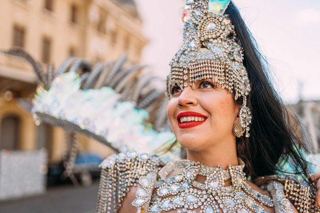 Hermosa mujer brasileña vistiendo coloridos trajes de carnaval y sonriendo durante el desfile de Carnaval en la ciudad.