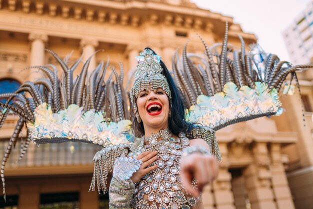 Hermosa mujer brasileña vistiendo coloridos trajes de carnaval y sonriendo durante el desfile de Carnaval en la ciudad.