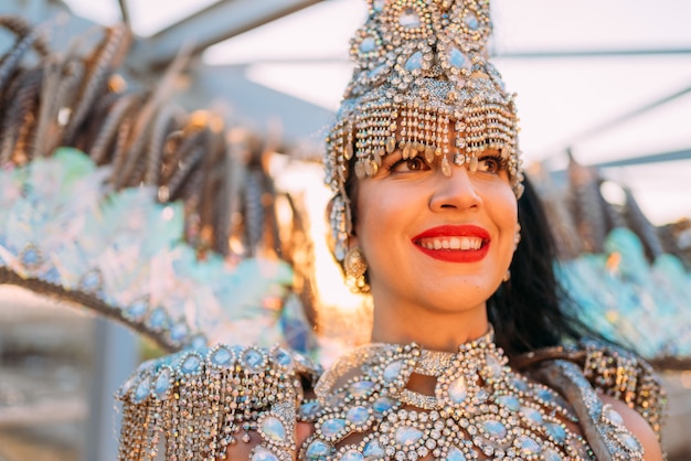 Hermosa mujer brasileña vistiendo coloridos trajes de carnaval y sonriendo durante el desfile de Carnaval en la ciudad.