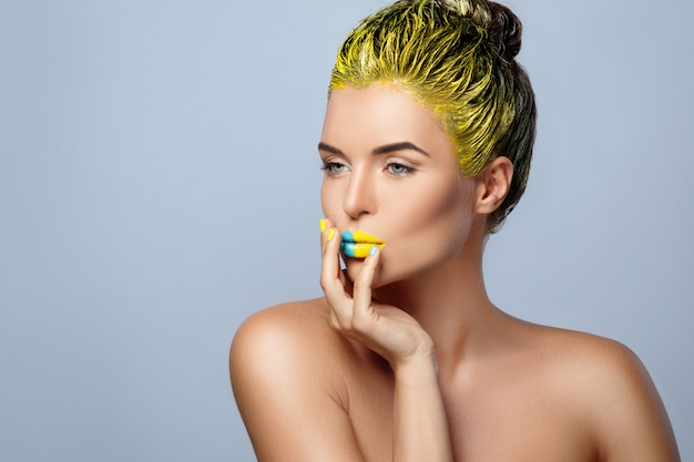 Hermosa mujer con cabello amarillo y coloridas uñas y labios