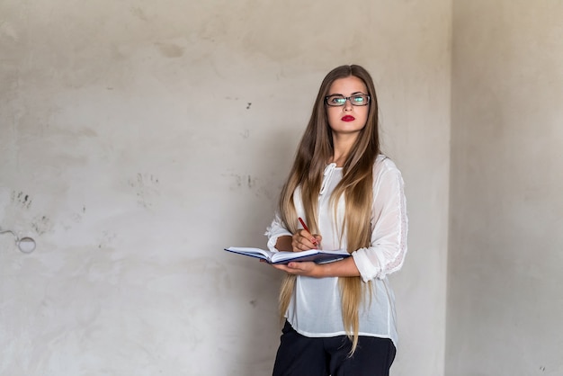 Hermosa mujer con cabello largo con bloc de notas y lápiz