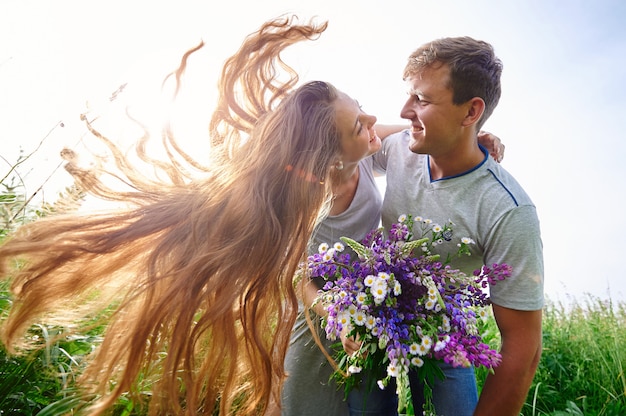 Hermosa mujer con cabello largo y un hombre feliz abrazando en campo