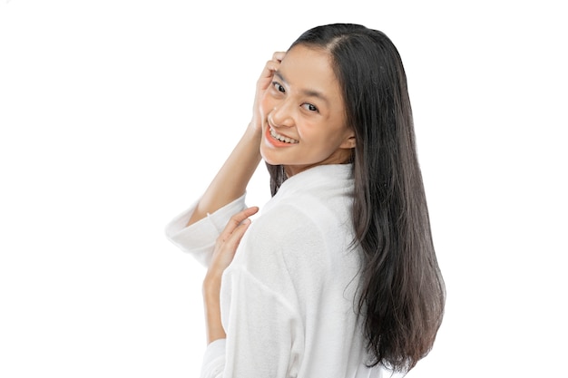 Hermosa mujer con cabello largo de pie hacia los lados mirando por encima del hombro a la cámara con una sonrisa