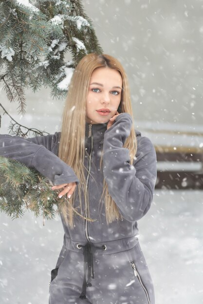 Hermosa mujer con cabello largo posando en el bosque en tiempo de nieve