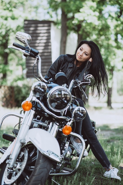 Hermosa mujer con cabello largo en ropa de cuero al aire libre en un día de verano. mujer biker