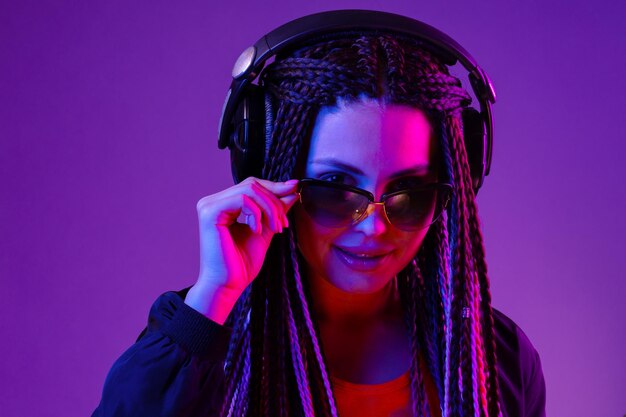 Hermosa mujer con cabello largo en trenzas escuchando música con auriculares