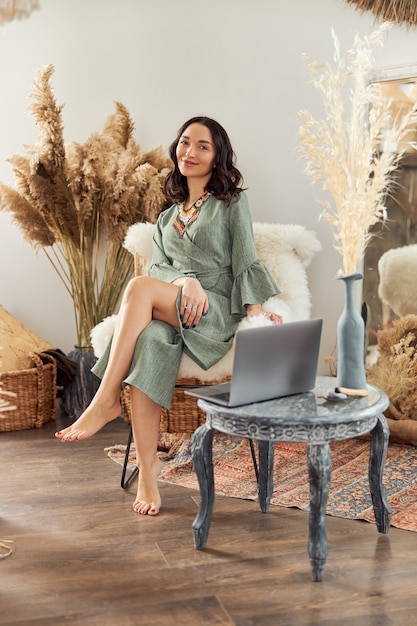 Hermosa mujer de cabello oscuro en traje étnico chamánico en habitación decorada al estilo de bali