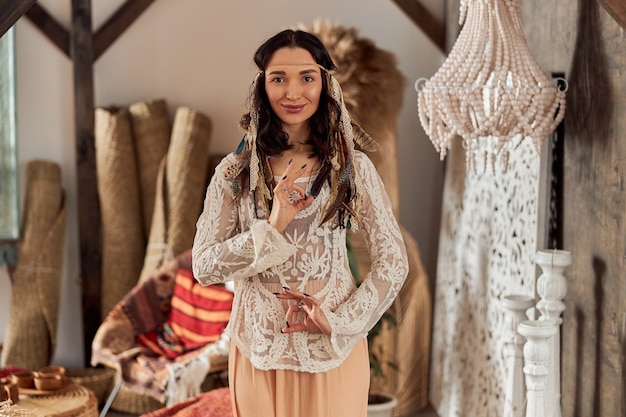 Hermosa mujer de cabello oscuro en traje étnico chamánico en habitación decorada al estilo de bali