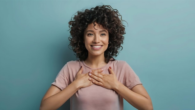 Foto una hermosa mujer de cabello rizado presiona las palmas del pecho hace un gesto de gratitud gracias por la ayuda o elogios