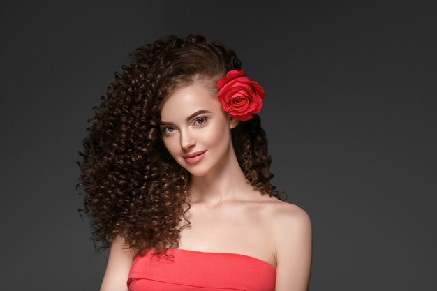 Hermosa mujer de cabello rizado en rojo con labios rojos y vestido de manicura, peinado afro rojo de belleza. Tiro del estudio.