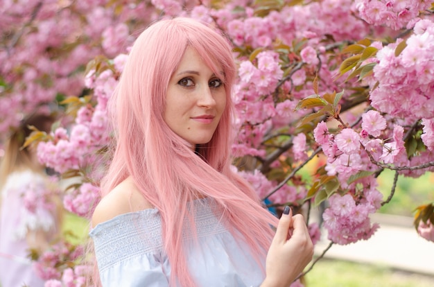 Hermosa mujer con cabello rosado en jardín de flores