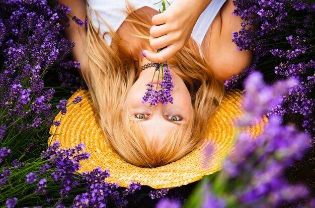 Hermosa mujer con cabello rubio está acostada en el campo de flores de lavanda