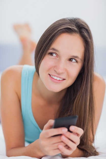 Hermosa mujer en la cama usando el teléfono