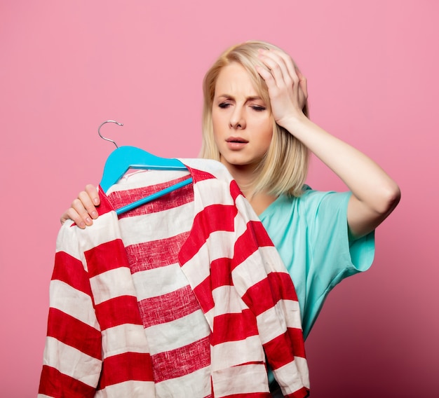 Hermosa mujer con camisa en una percha en pared rosa