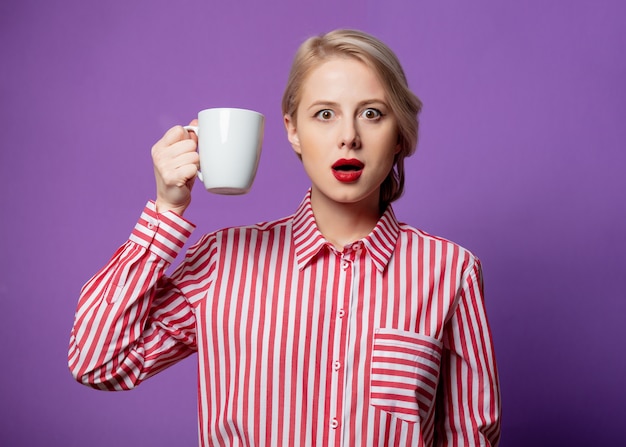 Hermosa mujer en camisa de rayas rojas con taza de café